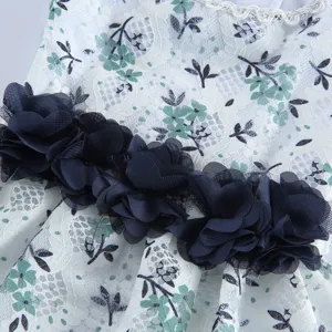 Vue détaillée de la robe pour animaux en dentelle blanche avec imprimé floral et fleurs bleues.