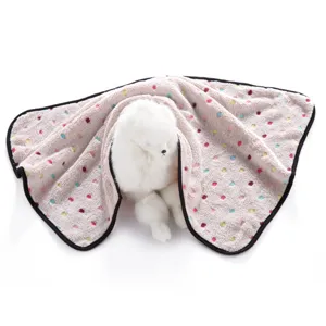Close-up detail of soft double-fleece pet blanket with colorful paw print pattern and black trim.
