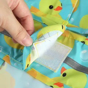 Close-up detail of cute duck print pet dog raincoat with Velcro closure and reflective strip.