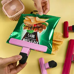 Detailed view of a pink plastic clip sealing a green snack bag on a yellow surface