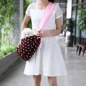 Detailed shot of pet sling bag, brown polka dot design with pink strap, outdoor scene.