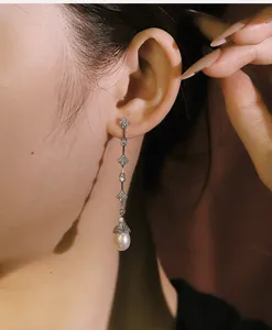 Primer plano detallado de elegantes pendientes colgantes de trébol con perlas en modelo