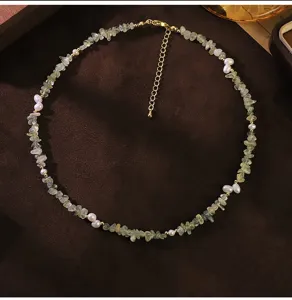 Primer plano detallado de collar con perlas naturales y prenita sobre fondo de terciopelo