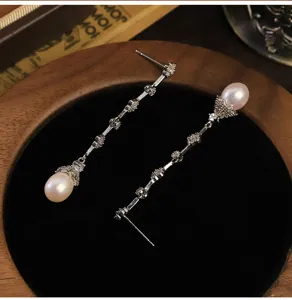Detalle de pendientes colgantes de trébol con perlas naturales y circonitas