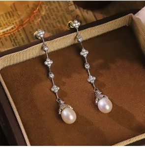 Detalle de pendientes de trébol en plata con elegantes perlas naturales blancas