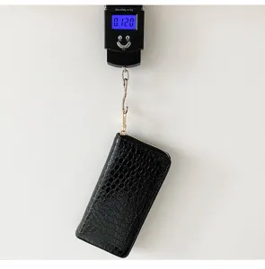 Cartera negra de mujer con patrón de cocodrilo pesando 120g en báscula