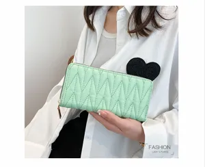 Detailansicht einer minzgrünen gesteppten langen Brieftasche für Damenmode in der Hand.