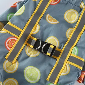 Gros plan détaillé du manteau imperméable pour animaux gris avec imprimé citron et sangles.