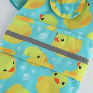 Detailed close-up of cute duck pattern pet raincoat with reflective safety strip and hood.