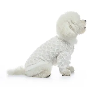 Vista laterale di un piccolo cane bianco con vestiti estivi in rete bianca traforata