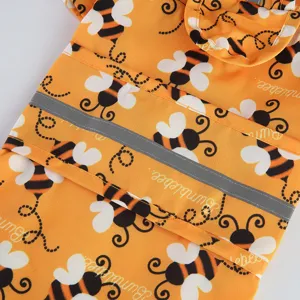 Close-up detail of cute bee print pet raincoat fabric with reflective safety stripe.