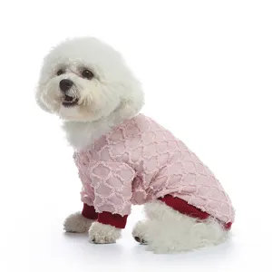 Vista laterale di un Bichon bianco con una maglietta rosa traforata con polsini rossi.