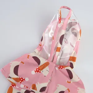 Cute pink pet dog raincoat with transparent hood and cartoon print. Waterproof two-legged gear.