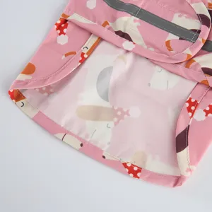 Close-up detail of pink pet dog raincoat waterproof fabric with cute cartoon print and reflective strip.