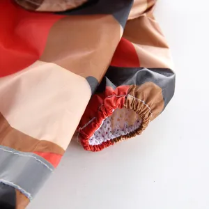 Détail imperméable pour chien, veste colorée à carreaux avec poignets élastiques et bandes.