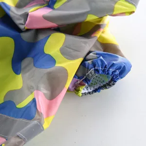 Détail de manteau de pluie pour chien imperméable avec tissu camouflage et bandes réfléchissantes.