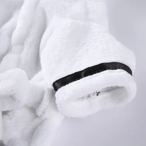 Macro detail of white plush pet bathrobe showing soft texture and black ribbon cuff