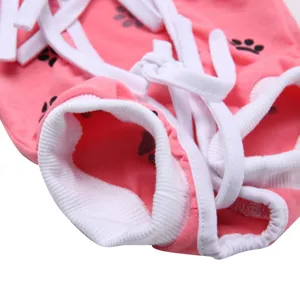 Pink pet surgical recovery suit detail close-up with secure straps and cute paw print pattern.