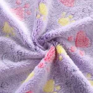 Soft plush pet blanket detail showing purple fleece with cute pink and yellow paw prints.
