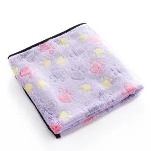 Close-up of soft plush pet blanket with cute colorful paw print pattern and neat black edge.