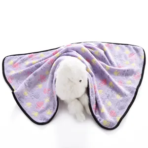 Close-up detail view of soft fleece pet blanket with cute paw prints and neat black edge trim.