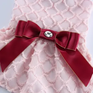Detail de robe de chien de compagnie en maille rose avec noeud satin rouge et cristal fetes.