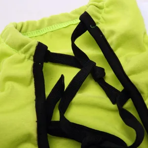 Detailed view of neon green pet recovery suit with black strap lacing design, soft fabric.