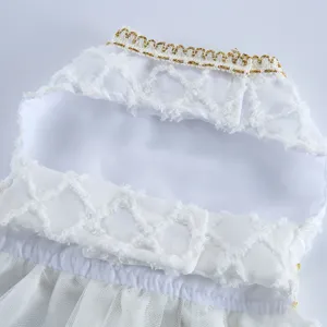 Vue détaillée de la robe pour chien blanche montrant la bordure dorée et le tulle.