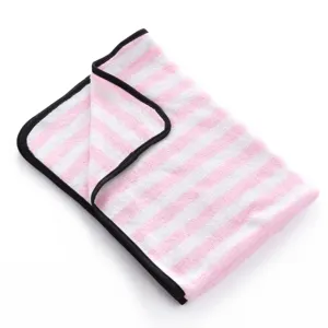 Close-up detail of soft pink and white striped pet blanket with neat black edging texture.