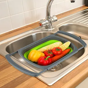 Grey and green foldable extendable colander for kitchen sink filled with fresh vegetables