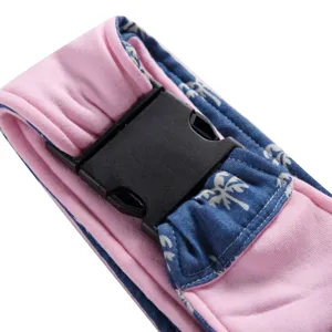 Pet carrier strap detail, pink and blue palm print fabric with durable black plastic buckle.