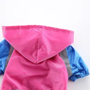 Gros plan sur l'imperméable pour chien coloré avec capuche rose et bandes réfléchissantes.