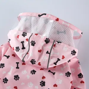 Manteau de pluie rose pour animal de compagnie avec motifs d'os et de pattes, capuche transparente.