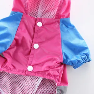 Détail de manteau de pluie rose et bleu pour chien avec boutons-pression et bande réfléchissante.