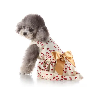 Cute pet summer dress detail, beige fabric with red hearts and large golden bow for dogs.