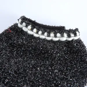 Gros plan de la robe pour chien en tissu noir pailleté avec élégante bordure de col tressée blanche.