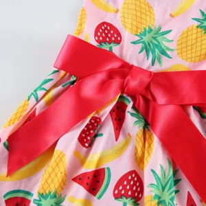 Close up of cute pink fruit print dress fabric featuring a vibrant large red satin bow.