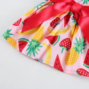 Close-up detail of lovely summer dress with colorful fruit print and big red bow.