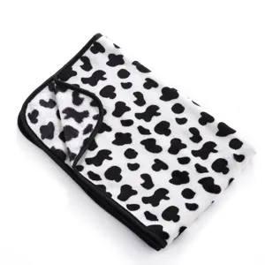 Soft fleece pet blanket detail, black and white cow print design with neat black binding.