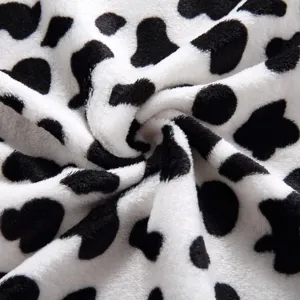 Soft black and white cow print fleece pet blanket fabric detail, cozy and comfortable.