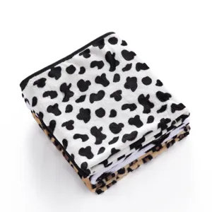 Soft fleece pet blanket with classic cow print design, warm and comfortable for cats and dogs.
