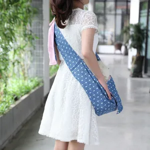 Detailed view of the breathable blue pet sling bag worn across the body, outdoor scene.