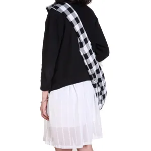 Detail view of the black and white plaid pet sling bag worn by model, showcasing the strap.