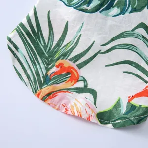 Nahaufnahme des tropischen Flamingo- und Palmenblattmusters auf dem weißen Hundesommerhemd