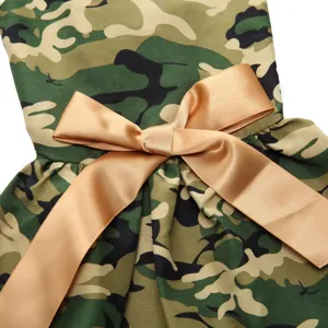 Close-up detail of a camouflage print pet dress featuring a decorative golden satin bow