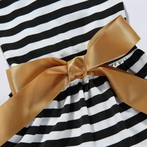 Detail of pet summer dress featuring black white stripes and a large golden satin bow