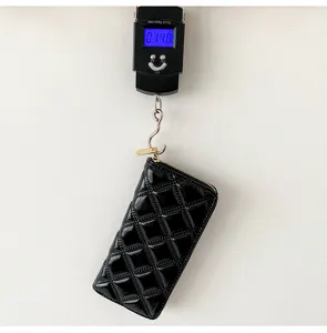 Black quilted patent leather long wallet being weighed on digital scale showing 140g weight