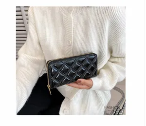 A detailed macro view of a glossy black quilted patent leather long wallet for ladies