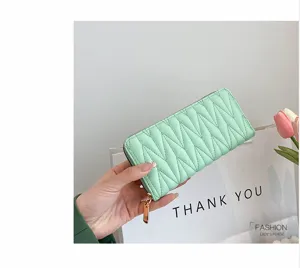 Nahaufnahme einer minzgrünen, bestickten langen Reißverschlussbörse für Damen in der Hand.