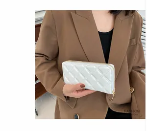 Close-up of white quilted ladies long wallet held in hand against brown blazer